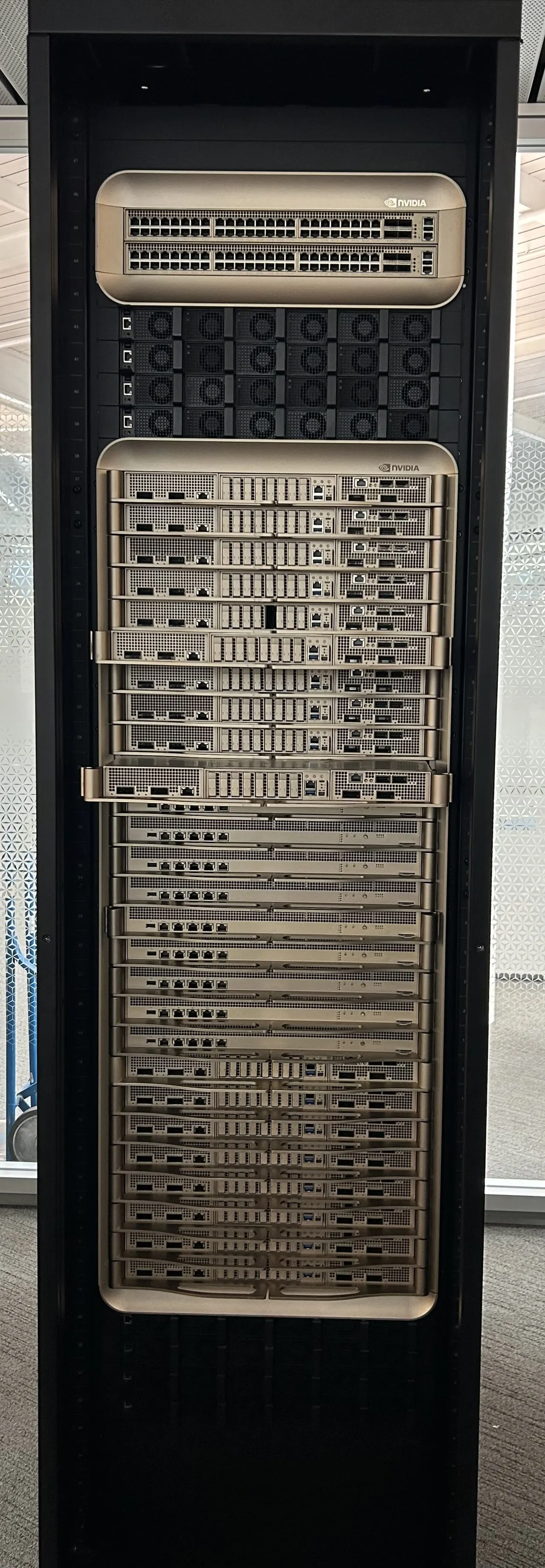 An NVIDIA GB200 liquid-cooled server rack with gold-finished compute trays and network switches